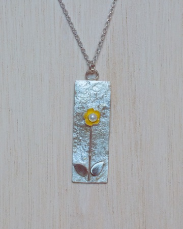 large silver pendant with a gold flower and pearl